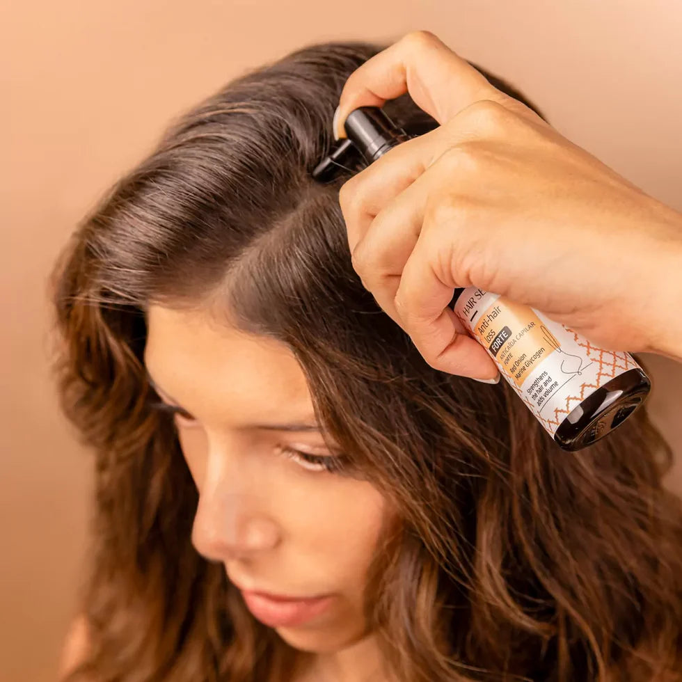 Frau trägt Nuggela & Sulé Anti-Hair Loss Serum Forte mit dem Applikator direkt auf den Scheitel auf