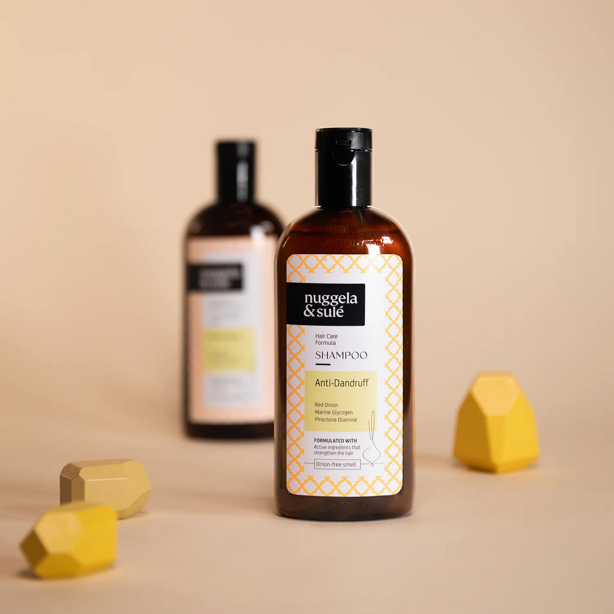 Faltschachtel und bernsteinfarbene Flasche des Nuggela & Sulé Anti-Schuppen-Shampoos 250 ml auf hellem Hintergrund